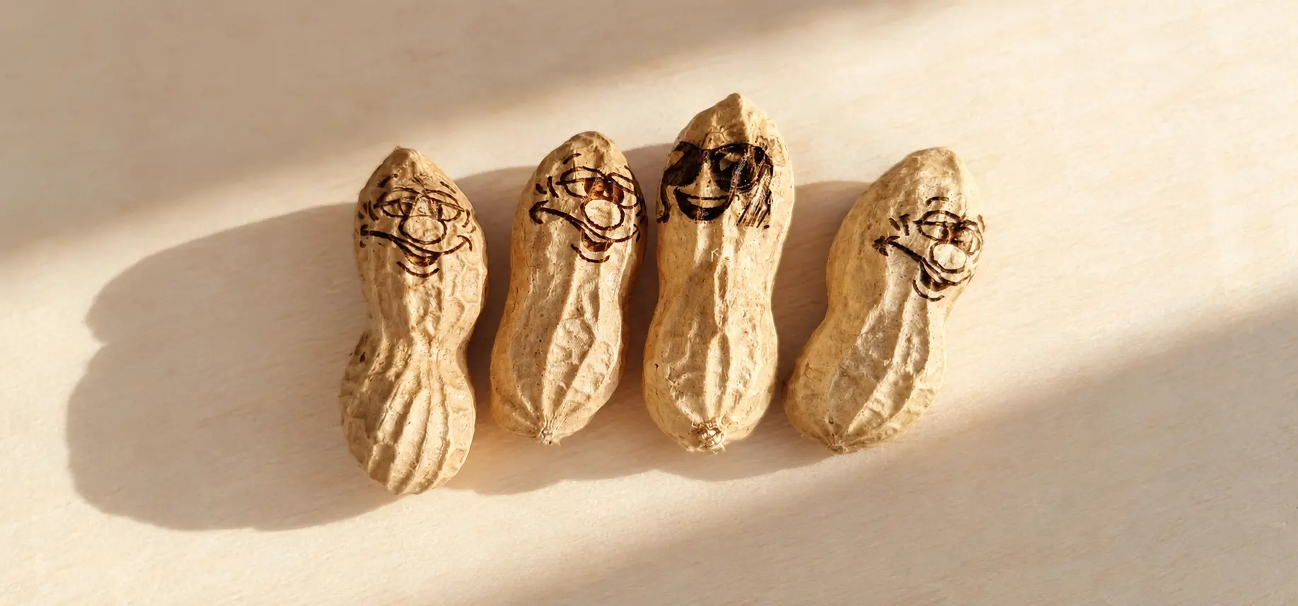 Four peanut shells engraved with different playful faces