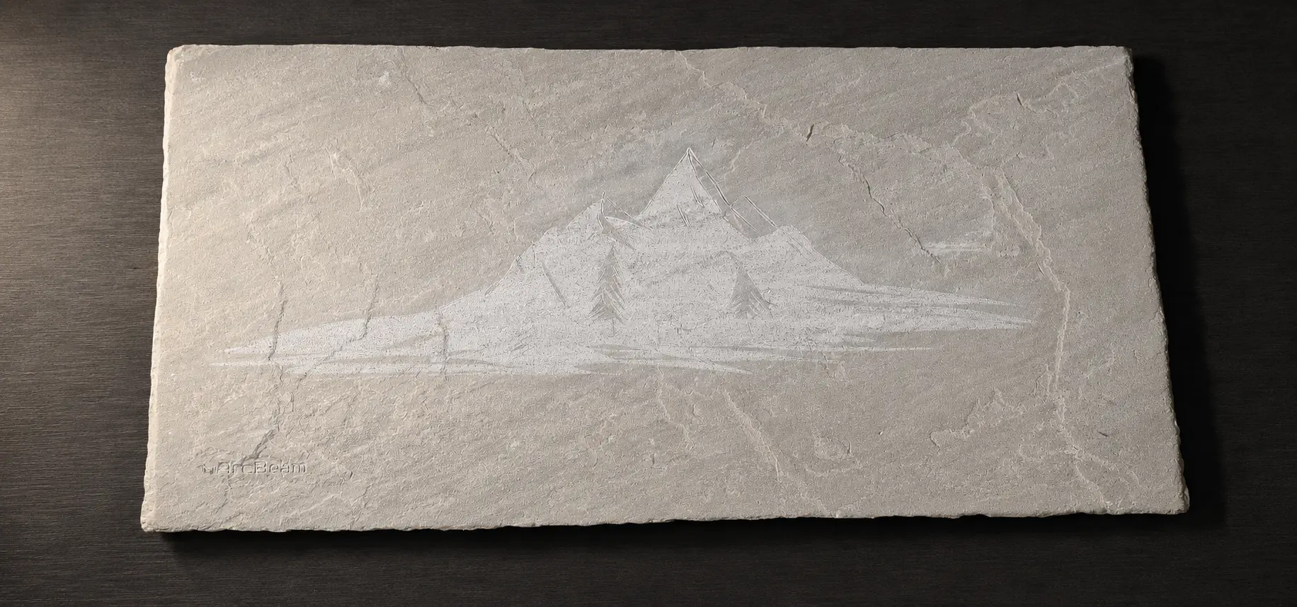Natural stone slab engraved with a subtle mountain landscape