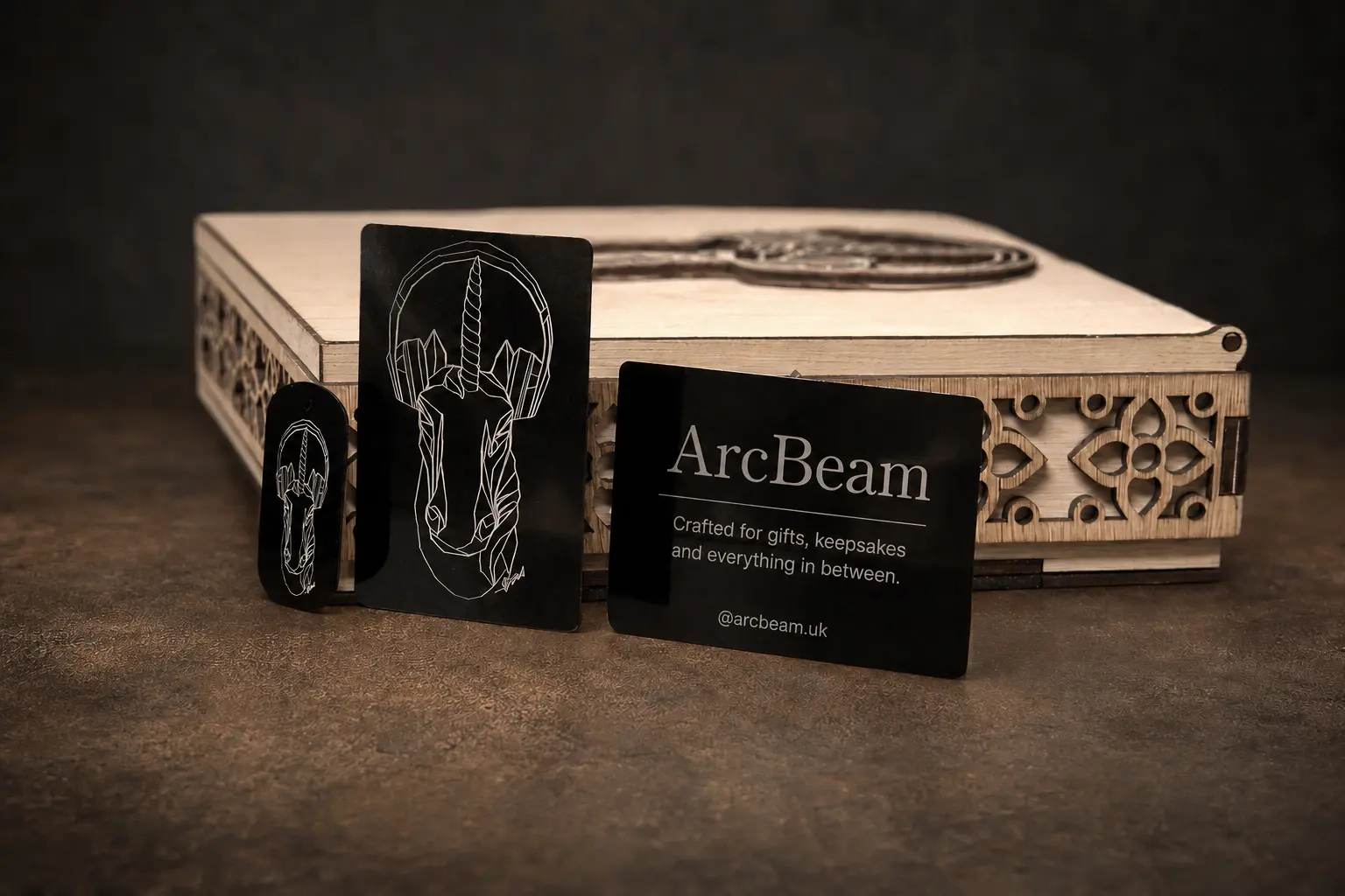 Laser-cut wooden presentation box with engraved black metal cards and a matching tag